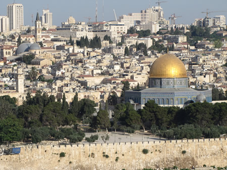 A view of Jerusalem from the Mount of Olives. The two grey domes to the far left are roofs over Calvary and tomb of Jesus in the Church of the Holy Sepulcher. The gold dome of the Dome of the Rock sets where the Jewish temple stood on the Temple Mount.