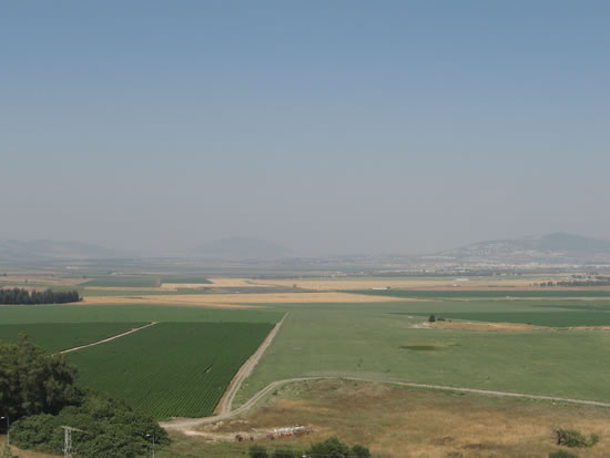 As seen in Toni's labeling: The hill to the left is where Nazareth is located. The hill in the middle is Mt. Tabor.  To the right is Mt. Moreh with the city of Endor on the back side of it.  The very large valley in front extens all the way to Mt. Carmel in the west and the Jordan Valley in the east is called Jezreel Valley.  Toni is standing in the ancient ruins of Megiddo looking down.